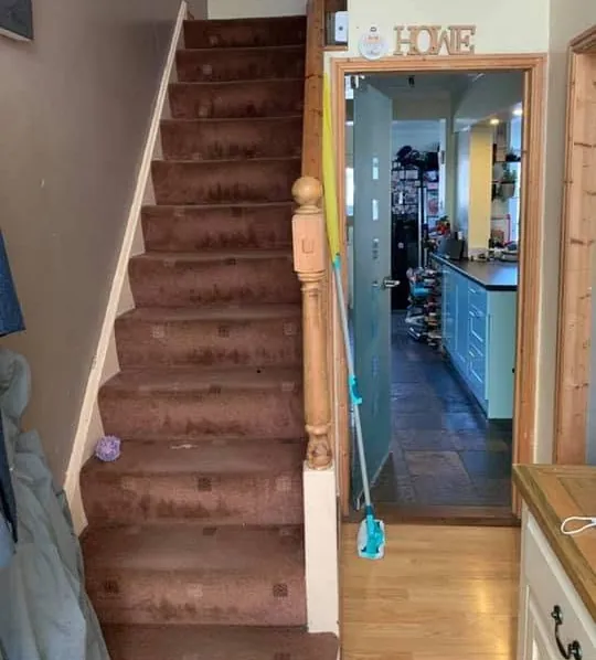 Staircase before decorating, with dated varnished timber and worn walls