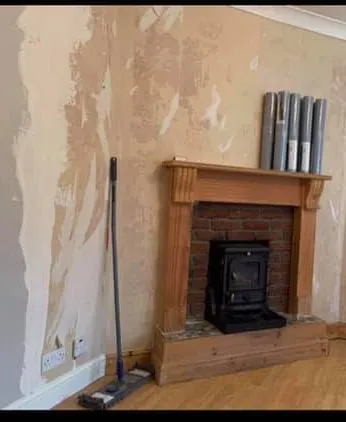 Living room before decorating, with damaged plaster around the chimney breast