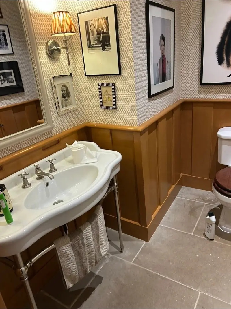 Bathroom with painted timber wall panelling, a traditional basin and framed prints above
