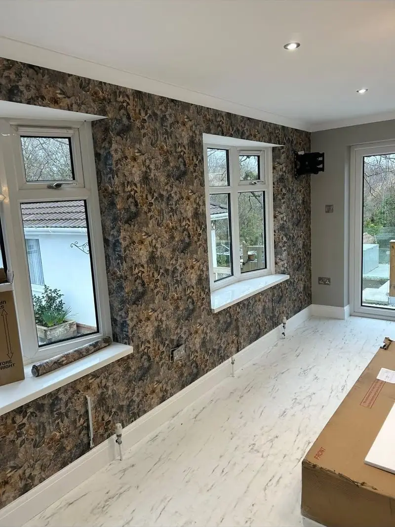 Dark floral wallpaper hung across a bedroom wall and around the window reveal