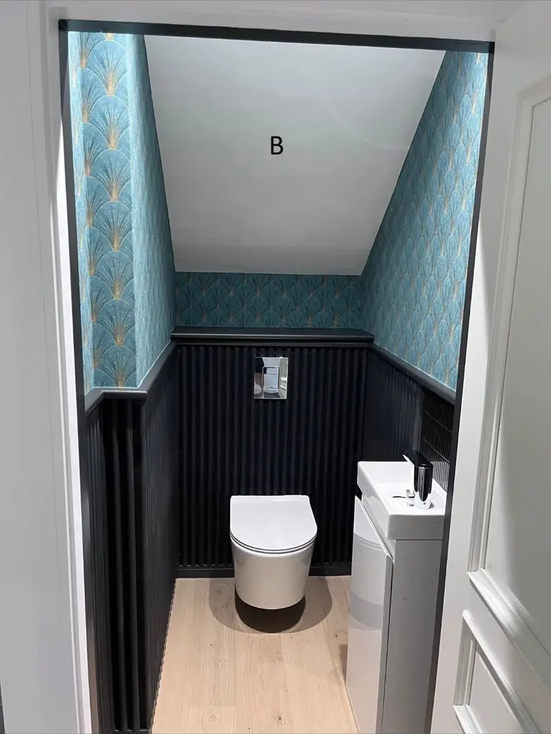 Downstairs cloakroom with dark painted panelling and a teal papered upper wall