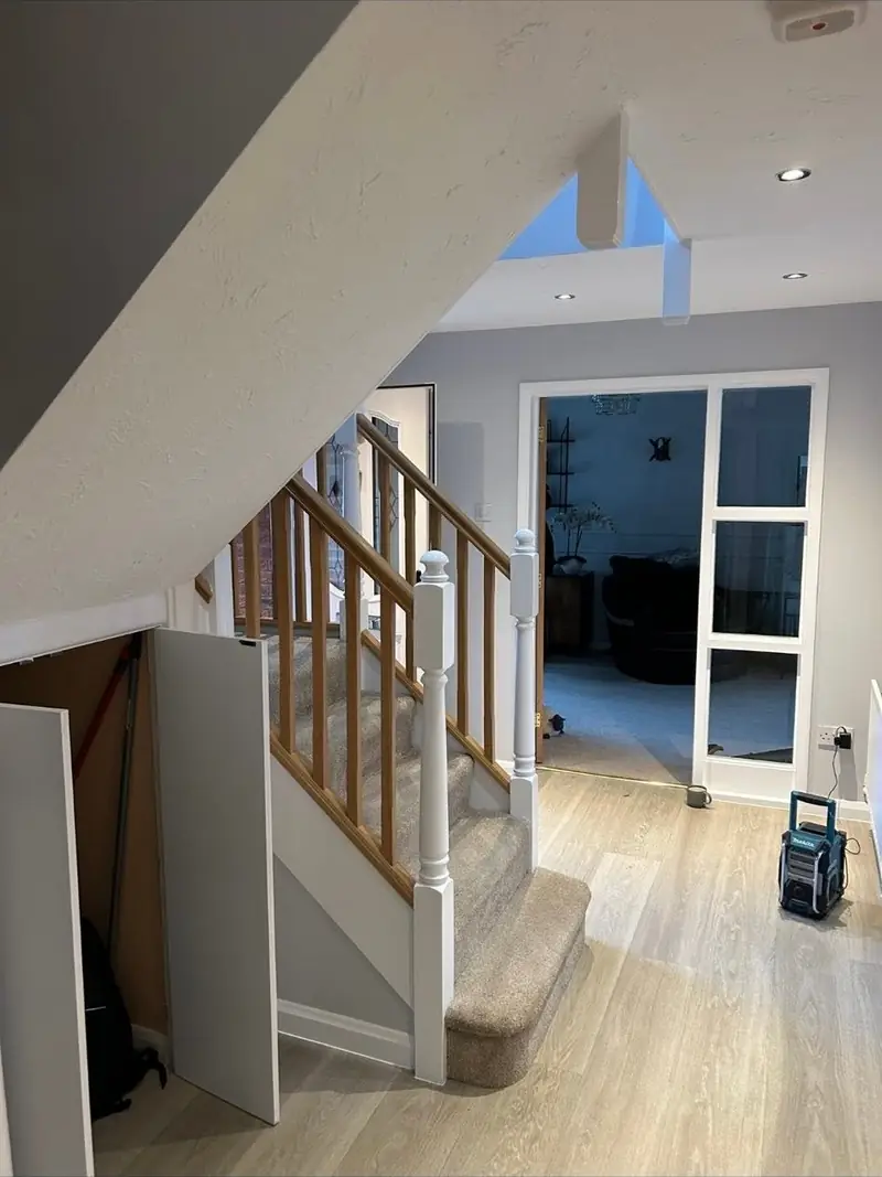 Hallway repainted with white staircase spindles, an oak handrail and a glazed internal door
