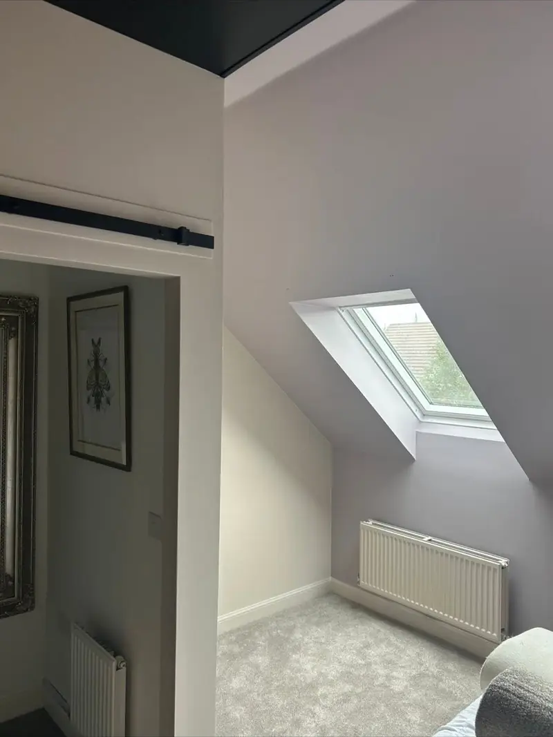 Loft bedroom decorated in warm grey with a sloped ceiling and a velux window