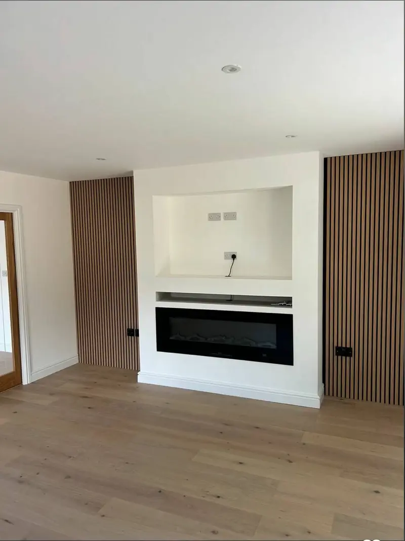 Slatted wood panelling around an inset fireplace, painted and finished in a Hampshire living room