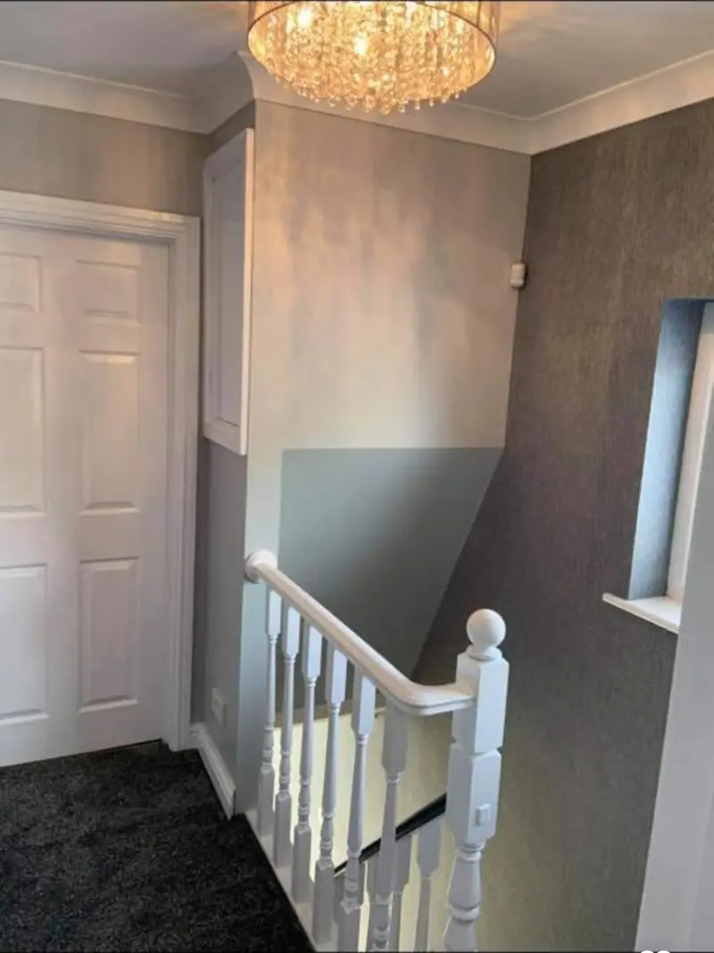 Stairwell and landing papered and painted from top to bottom with white spindles